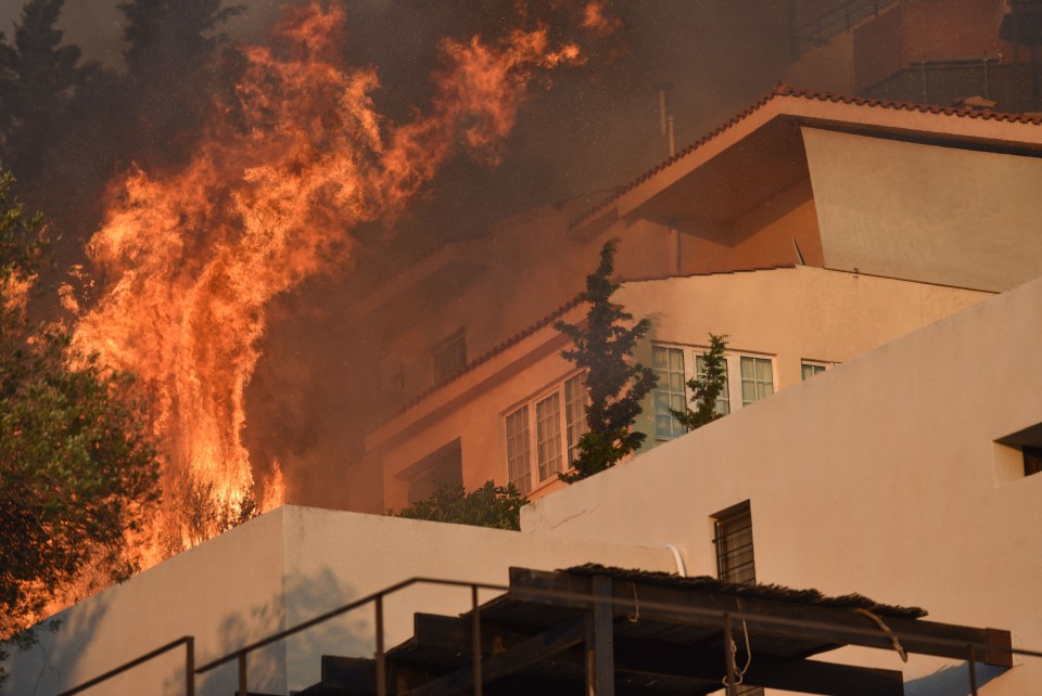 Flames have engulfed homes in Athens, Greece, as strong winds spur the wildfires on