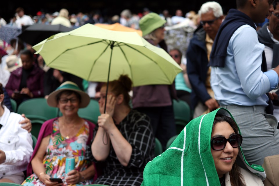 People took shelter from rain as play was suspended between Novak Djokovic of Serbia and Pedro Cachin of Argentina due to rain at the Wimbledon Championships yesterday