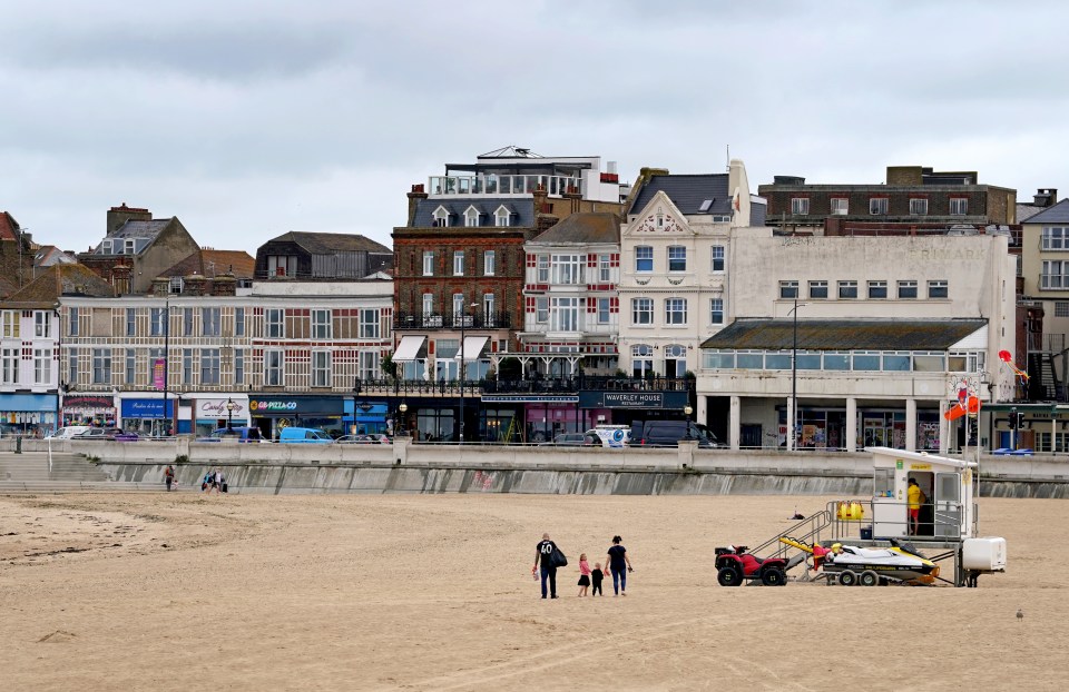 A family walk along the empty beach in Margate, Kent, during blustery weather on Monday morning