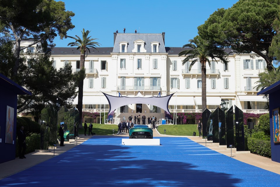 a car is parked on a blue carpet in front of a large building