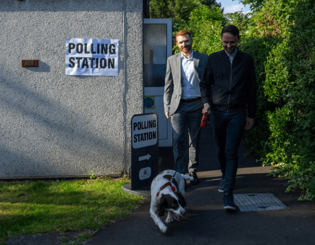 Danny Beales (L), the Labour Party candidate in Uxbridge, leaves a polling station with his housemate Joel Kenyon and dog Buddy