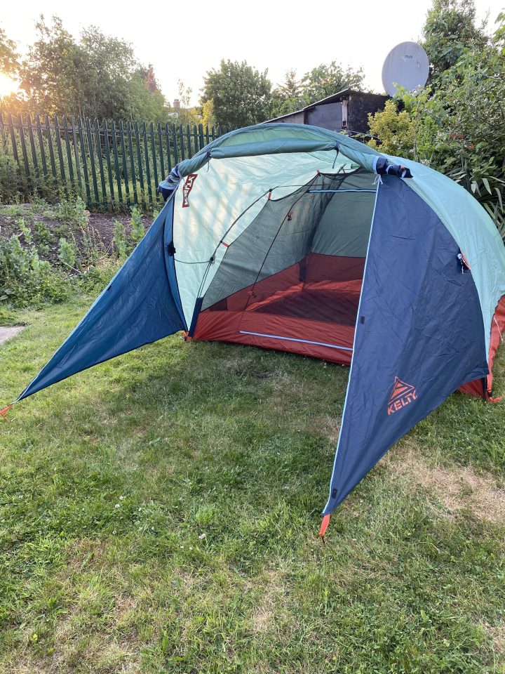 a kelly tent is sitting in the grass in front of a fence