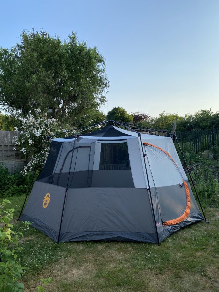 a coleman tent is set up in a backyard