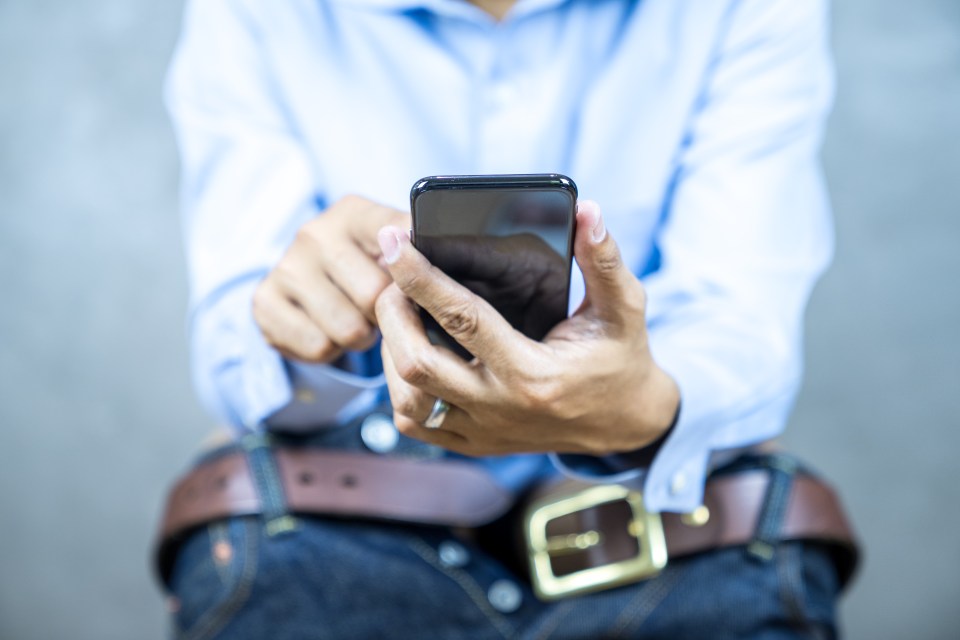 Man sitting toilet and holding smartphone