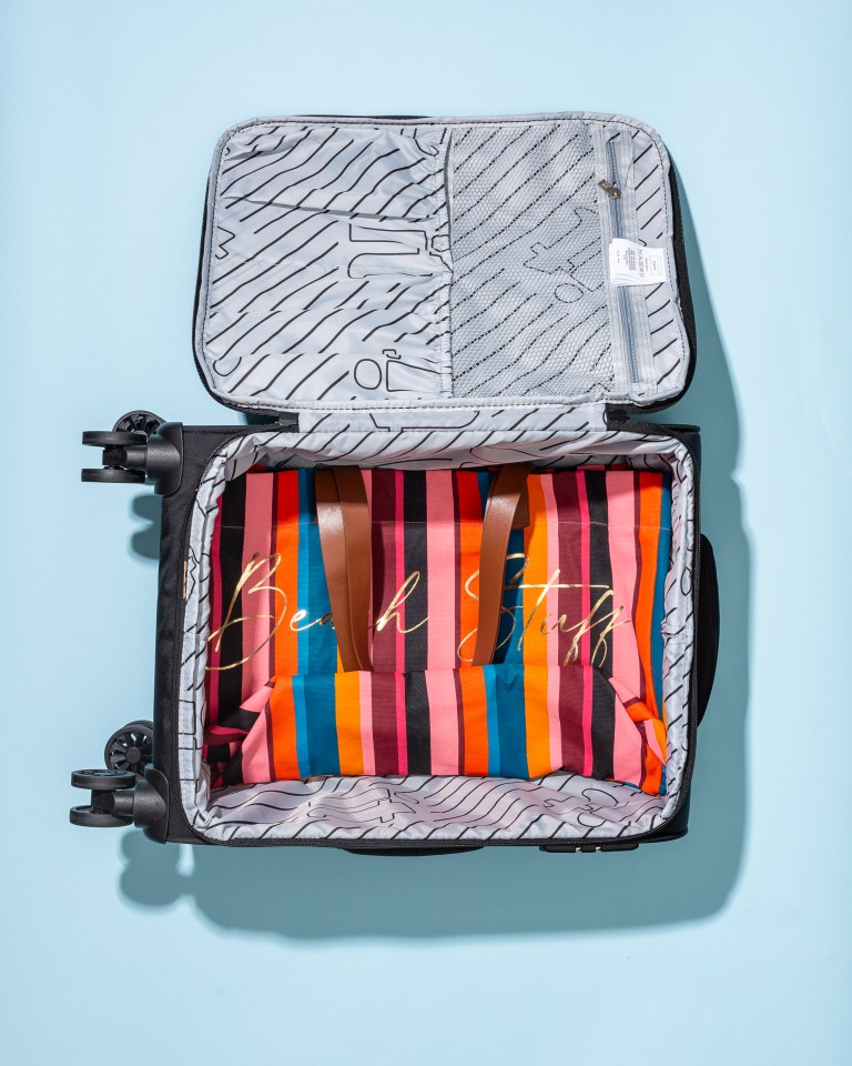 Fold a bag in half before placing it flat at the bottom of your suitcase