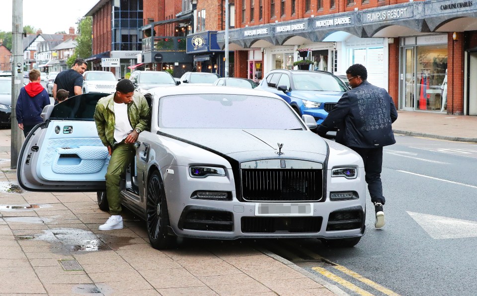 a man standing next to a silver rolls royce car