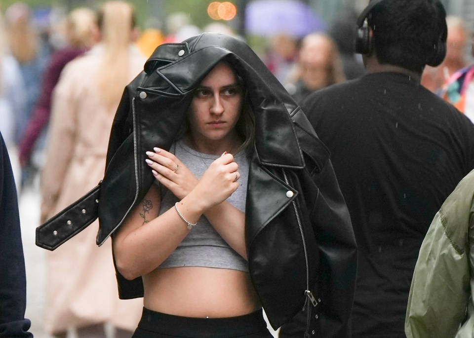 A woman peers out from under her jacket in Manchester on Monday