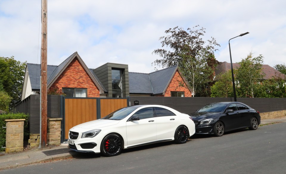 two cars are parked in front of a brick house