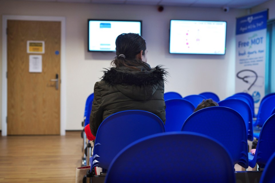 2GY6M20 One female mixed race patient sitting in a GP surgery waiting room during a pandemic