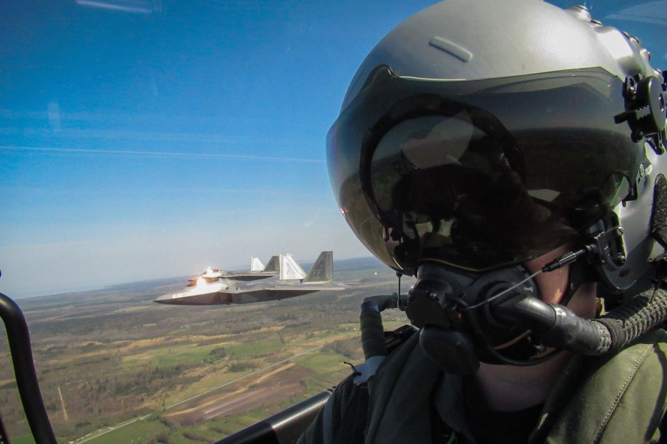 An RAF pilot seen posing alongside two USAF F-22 Raptors mid-flight in May this year