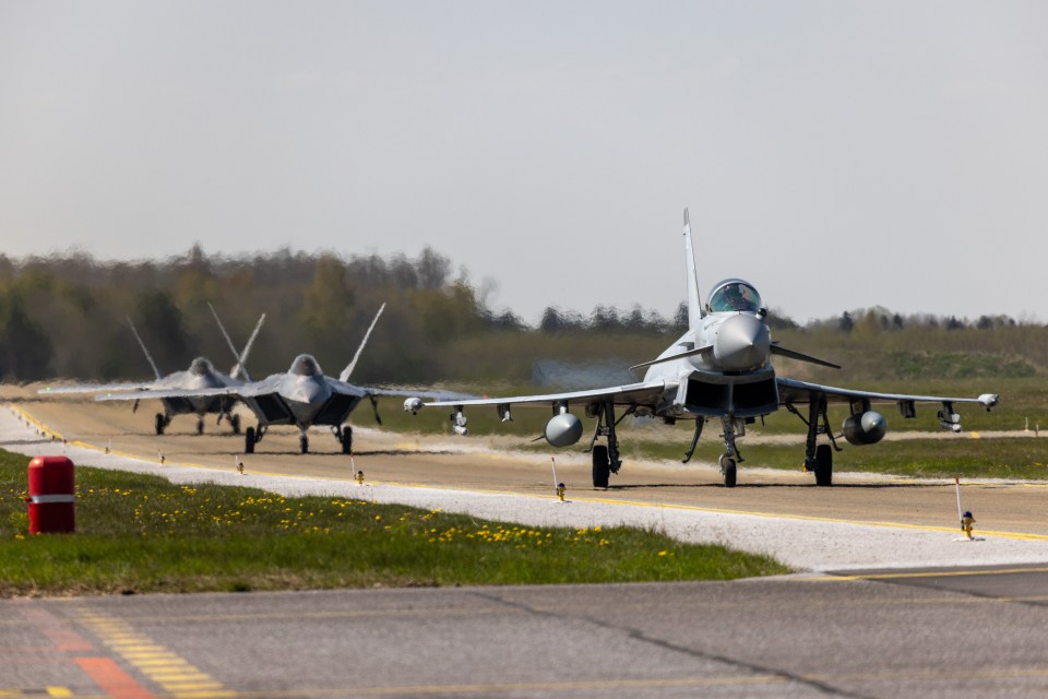 An RAF fighter jet, followed by two USAF F-22 Raptors, prepares for take-off in Estonia