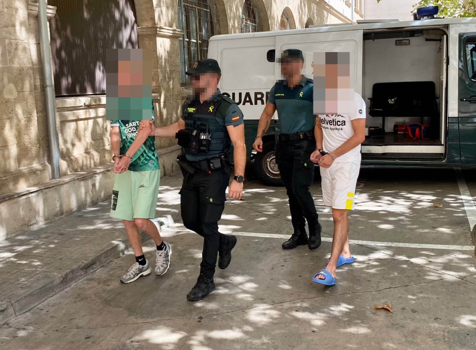 Two of the arrested men being led by the police in Palma