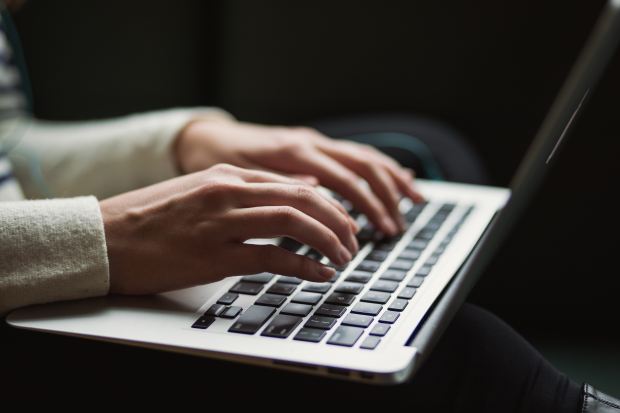 a person is typing on a laptop with the shift key visible