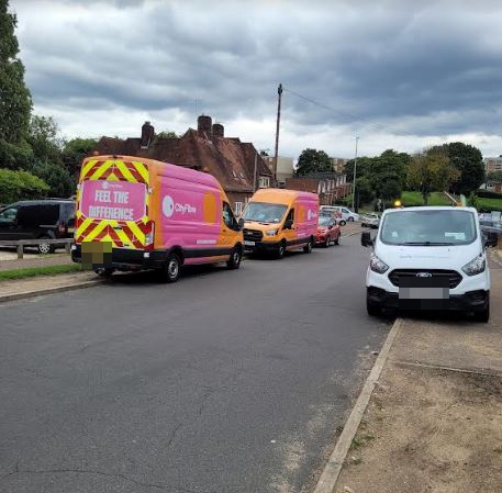 Cars parked on both sides of the road block it up