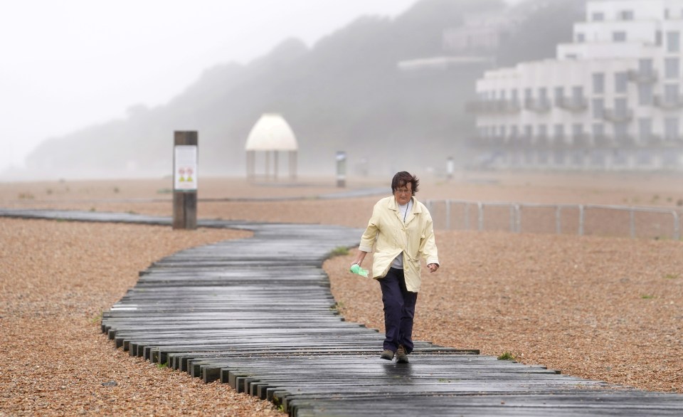 A lady walks along the beach during bad weather in Folkestone, Kent, on Monday - the town has a Yellow weather warning for wind on Wednesday