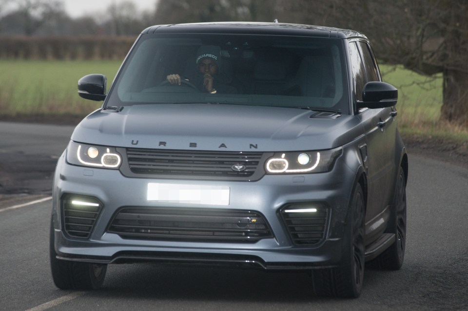 a man is driving a grey urban range rover