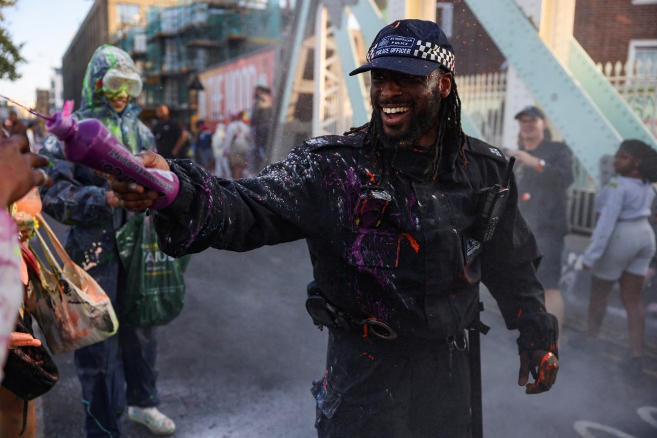 A cop joins in the fun and sprays paint during the traditional J'ouvert opening