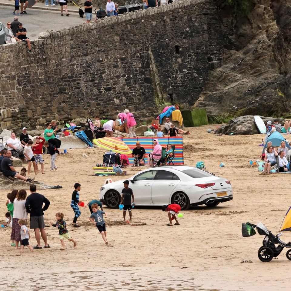 Beachgoers were seen surrounding the Mercedes on the beach