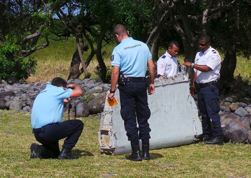 Police inspect a large piece of plane debris which was found on the beach in Saint-Andre, thought to be from the doomed jet