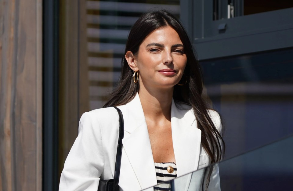 a woman wearing a white jacket and hoop earrings