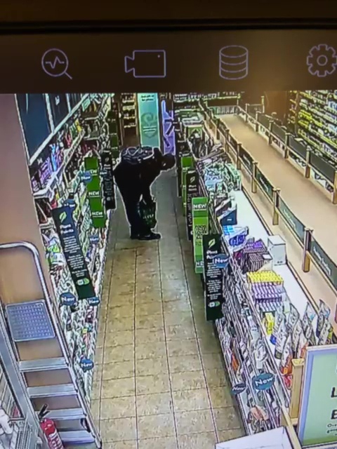 A shoplifter puts goods in a bag in Holland and Barrett