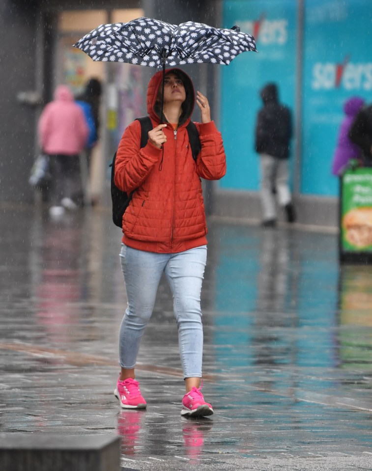 A woman tries to protect herself from the elements with a brolly in Bolton today