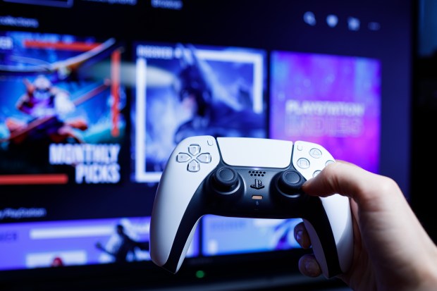 a person holding a playstation controller in front of a screen that says monthly picks