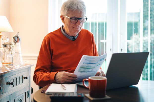 a man sitting at a table with a laptop and a cup of coffee