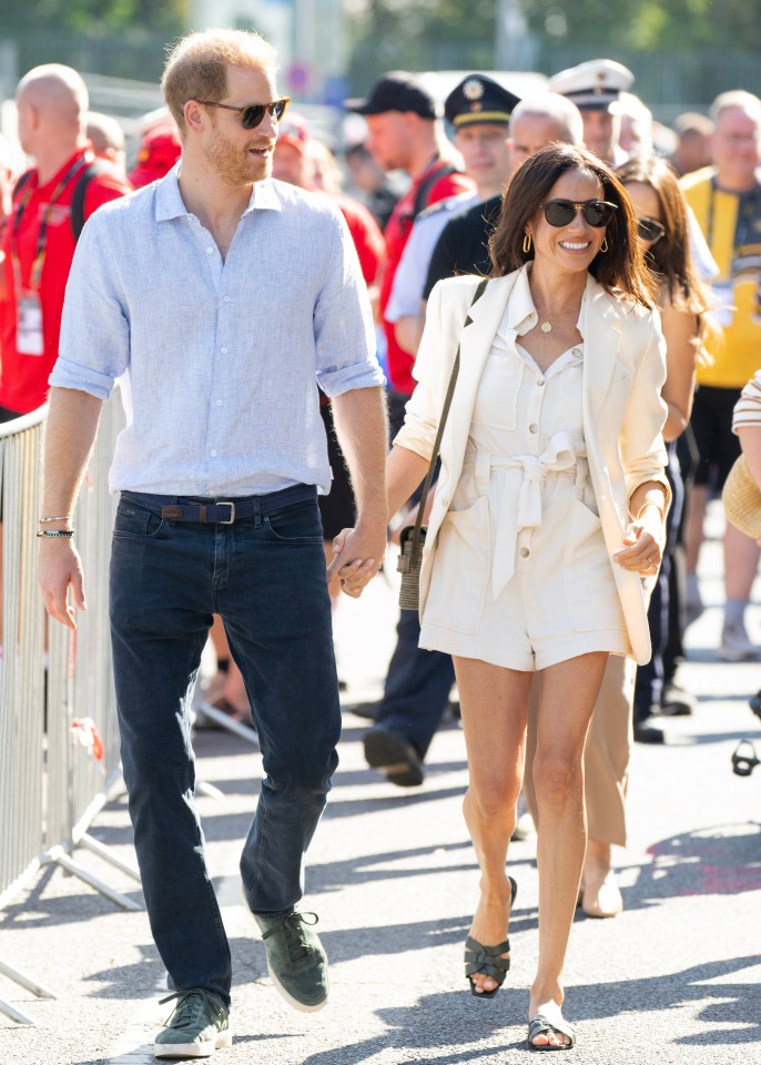 prince harry and meghan markle walk down the street holding hands