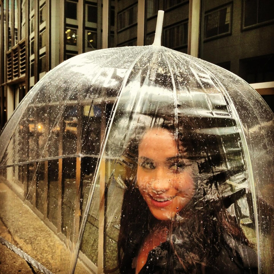 a woman stands under a clear umbrella in the rain