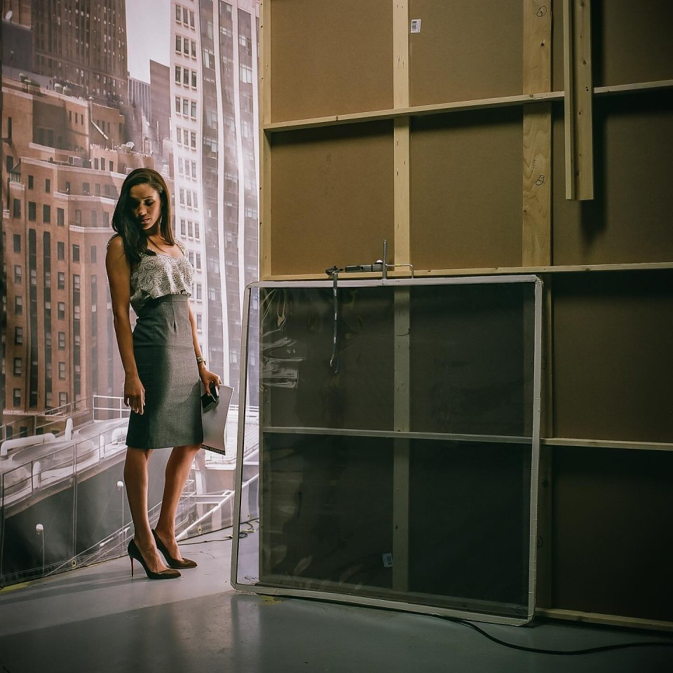 a woman stands in front of a wall with a picture of a city on it