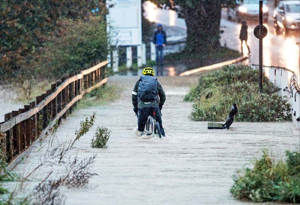 Pictured: A cyclist is submerged as he cycles through flooding in Ryde on the Isle of Wight