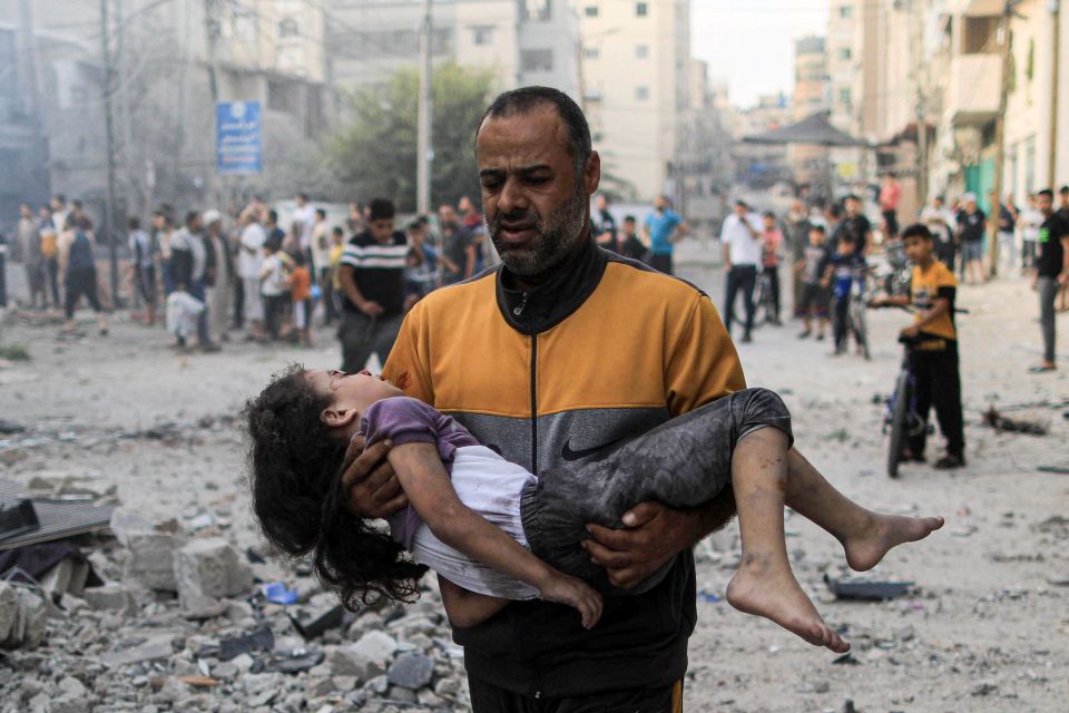 A Palestinian man carries an injured a girl following an Israeli strike in Khan Yunis, Gaza