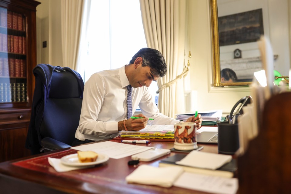 Rishi Sunak pictured working at his desk, with a slice of cake