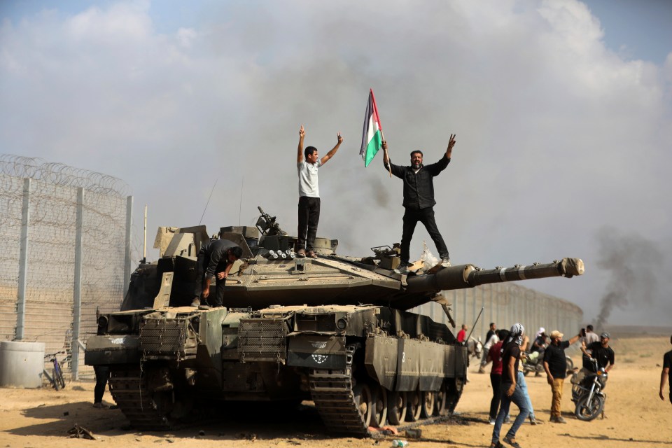 Palestinians celebrate on a destroyed Israeli tank in the Gaza Strip