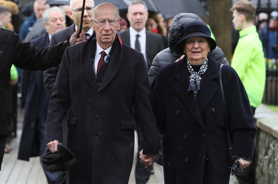 a man and a woman are walking in a crowd holding hands