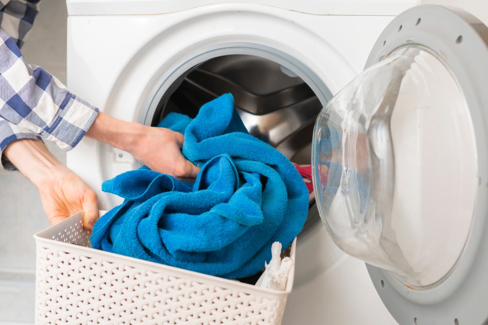 persons hand put dirty clothes in the washing machine