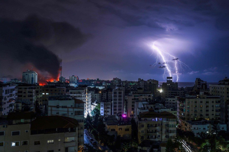 Lightning strikes as smoke billows following an Israeli airstrike in Gaza City