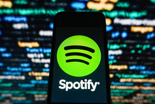 Mandatory Credit: Photo by Omar Marques/SOPA Images/Shutterstock (14163019m) In this photo illustration, a Spotify logo seen displayed on a smartphone with coding in the background. Illustration in Poland.