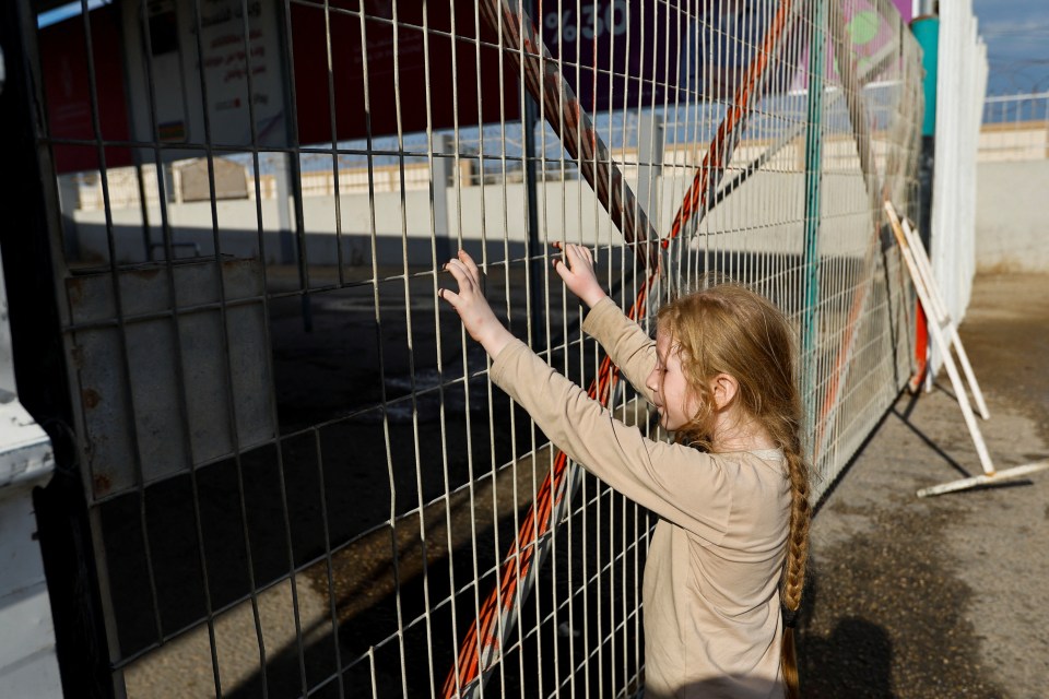 A Palestinian child waits outside the Rafah border crossing with Egypt amid the brutal conflict