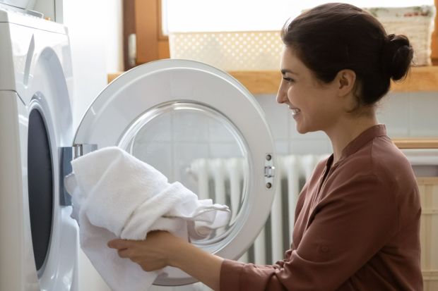 Woman putting a towel in a dryer.