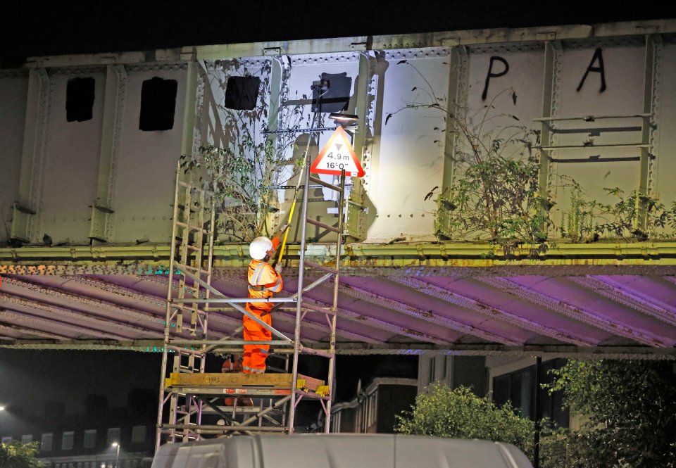 Cleaners remove 'Free Palestine' graffiti from a bridge in Golders Green