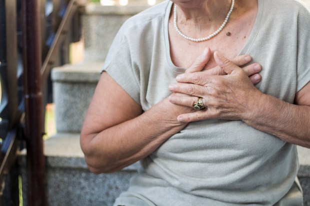 a woman with a pearl necklace is holding her chest