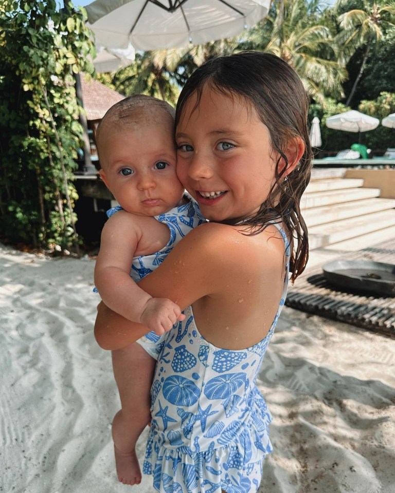 Her six-year-old daughter Sunday cradled her little sister Finty whilst on their most recent trip to The Maldives