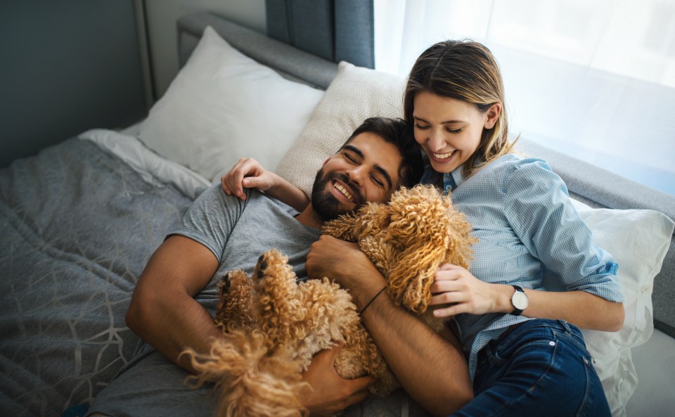 Closeup side view of a happy young couple at home having fun with their pet dog.