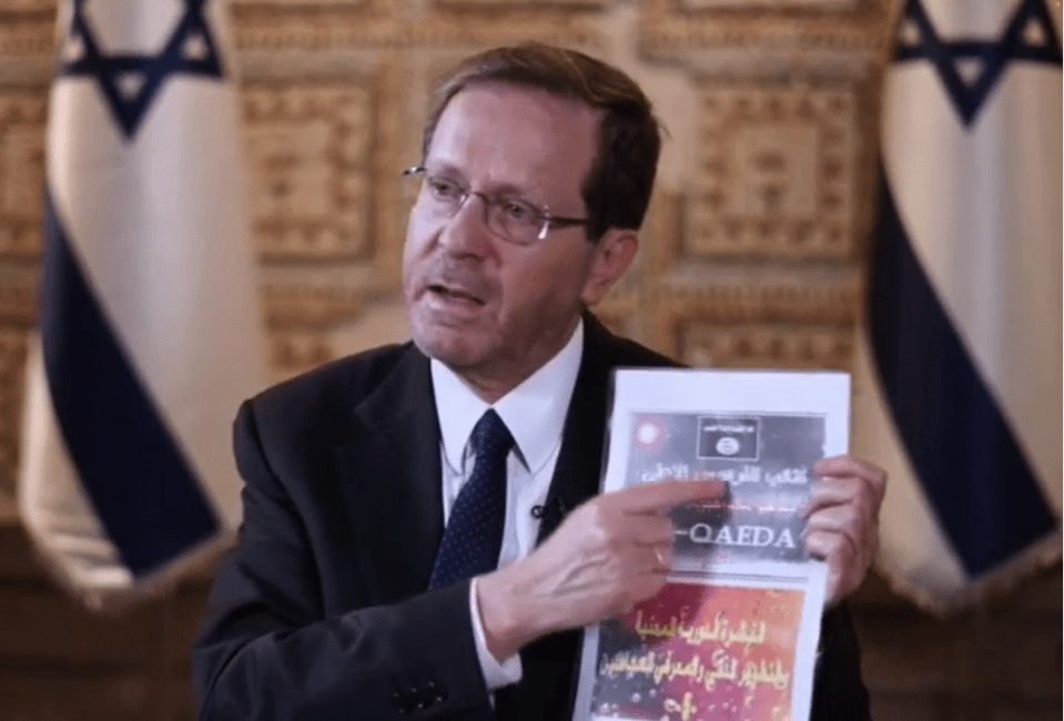 Israeli president Isaac Herzog holds up documents said to instruct Hamas terrorists how to build cyanide bombs with al-Qaeda's logo on