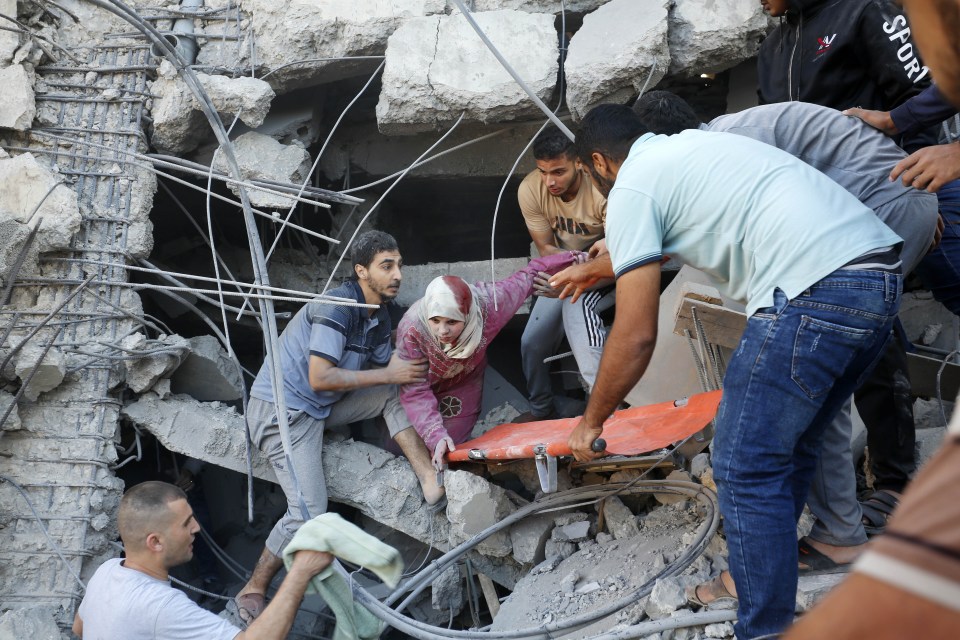 Palestinians try to save people from the debris after the Israeli airstrikes