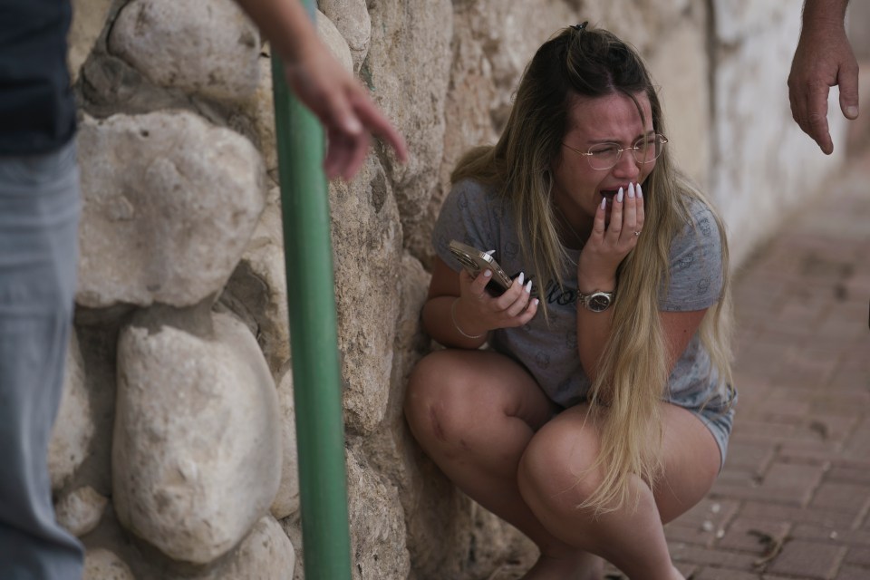 An Israeli woman sobs as citizens take cover amid incoming rocket fire from the Gaza Strip in Ashkelon, southern Israel