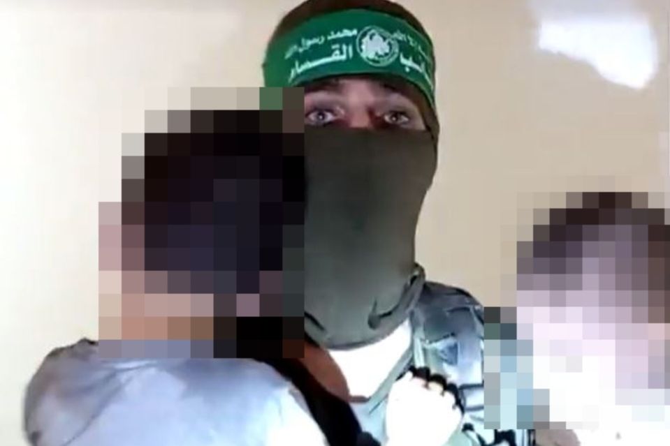 A Hamas fighter with kidnapped children following attack on a kibbutz