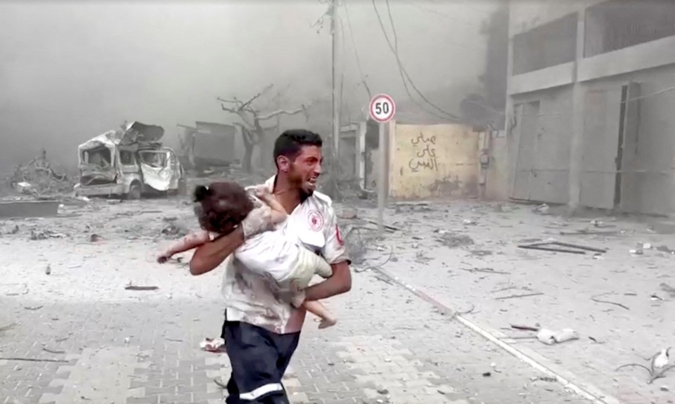 A medic runs as he carries an injured Palestinian child to an ambulance